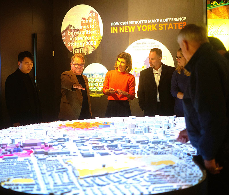 group of people look at an exhibit of the buildings located across a community buildings