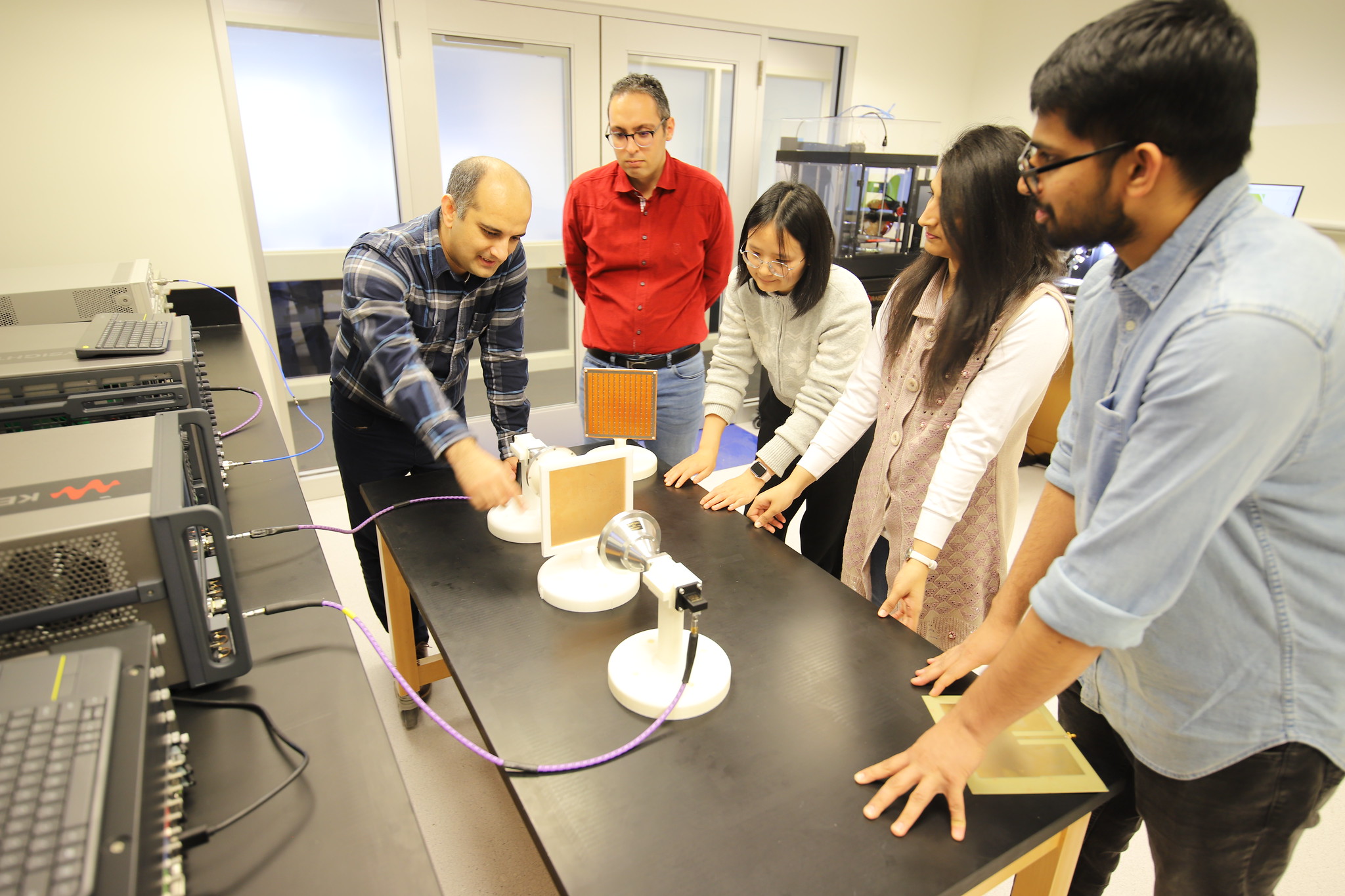 Professor and students gathered around a table working with scientific equipment.