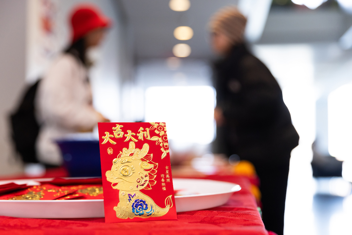Red card with a gold design on it being featured on a table with people talking in the background