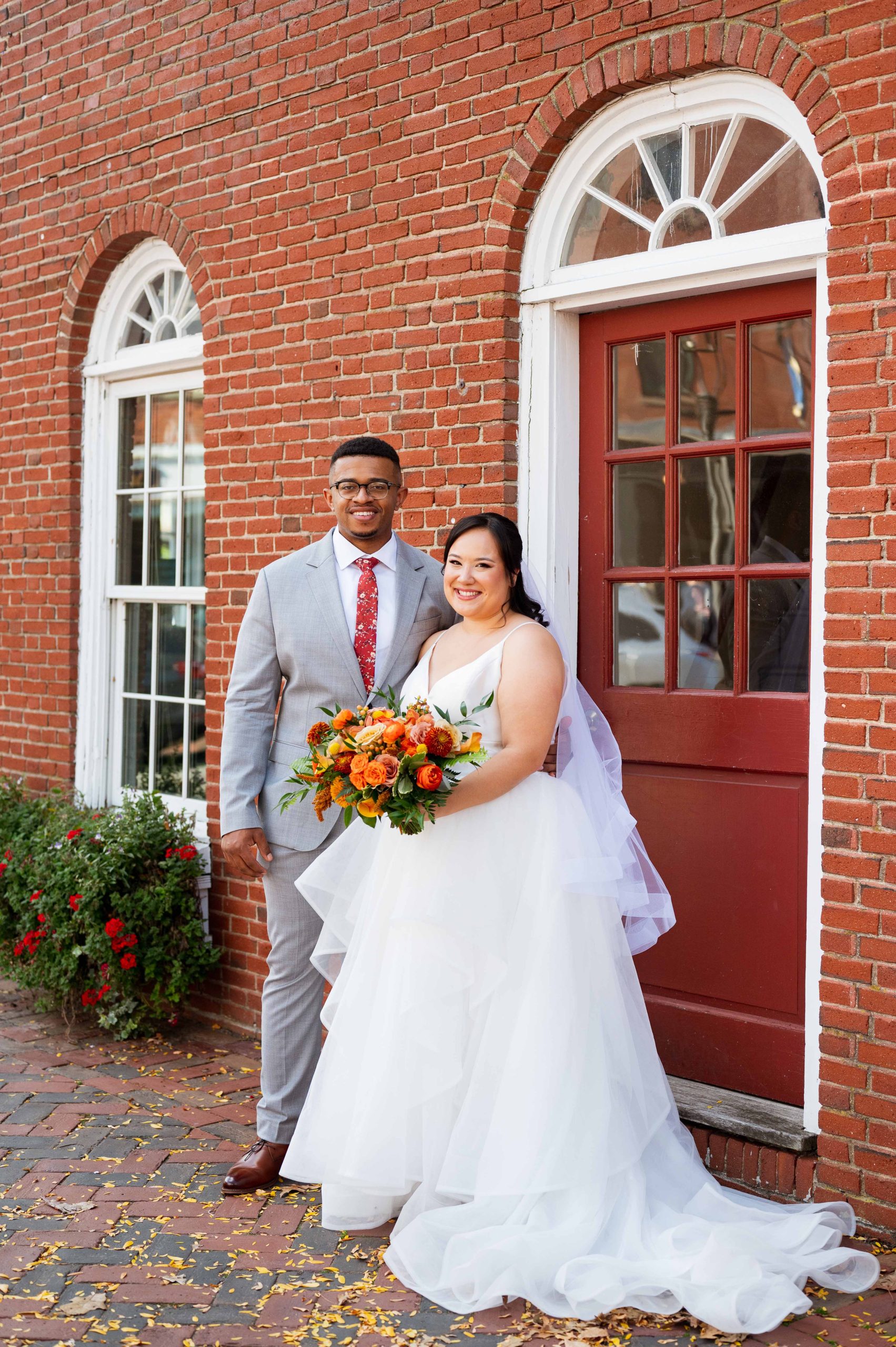 Bride and groom standing in front of a brick building.