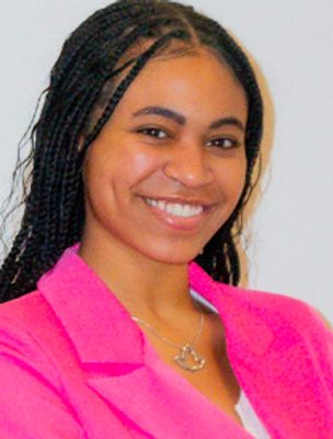A woman smiles while posing for a headshot indoors.