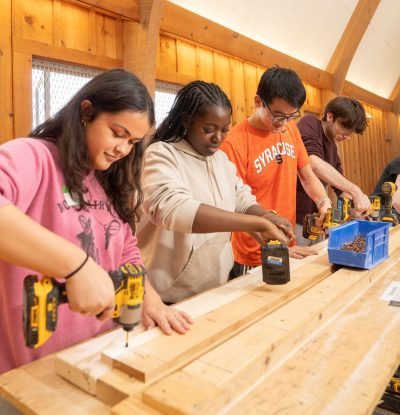four students working on drilling wooden boards