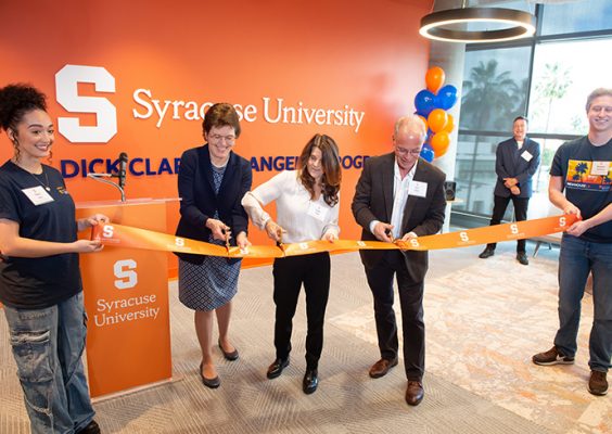 three people cutting ribbon, with two people holding ribbon at ends