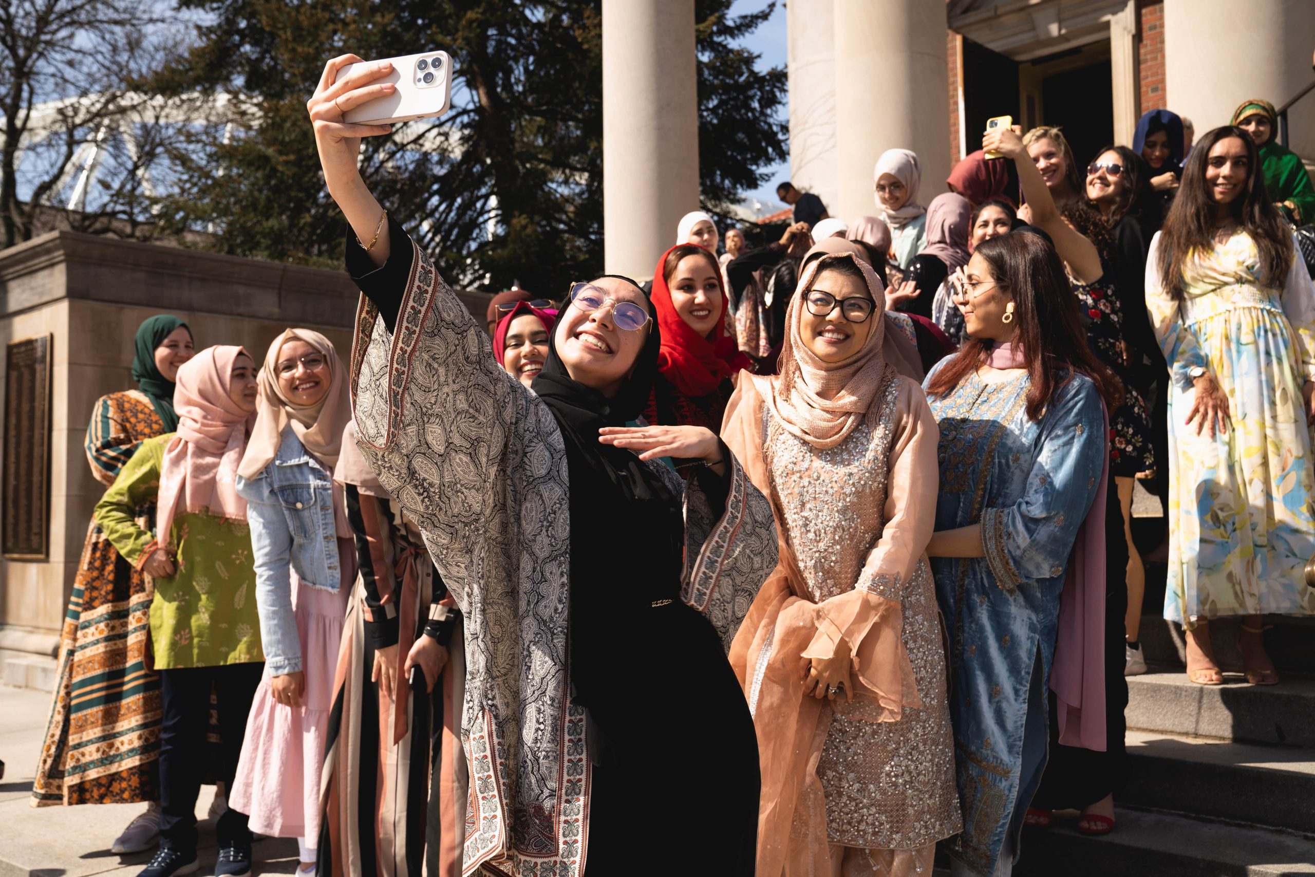 Muslim students smile and pose for a photo on the steps of Hendricks Chapel.