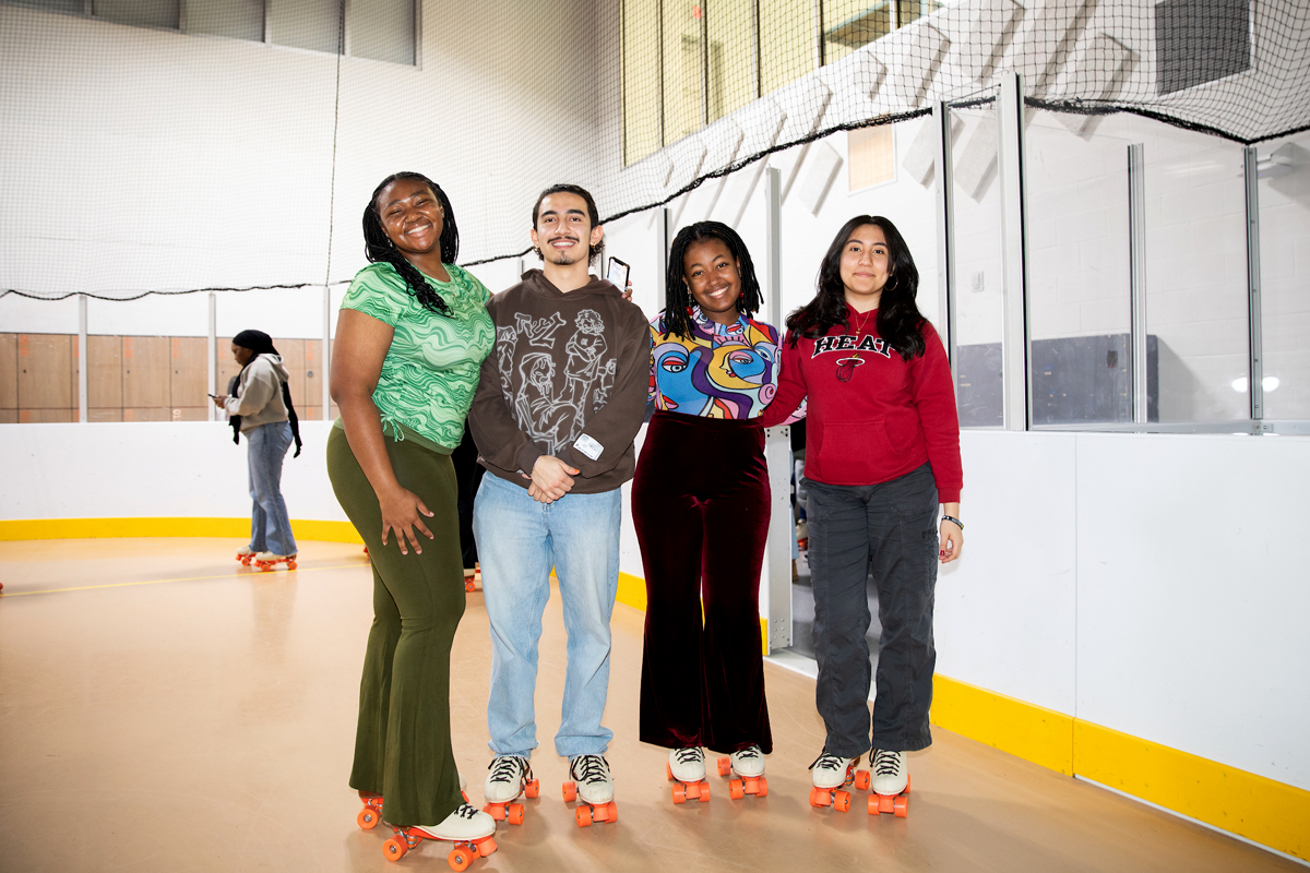 Four students pose for a photo while wearing roller skates.