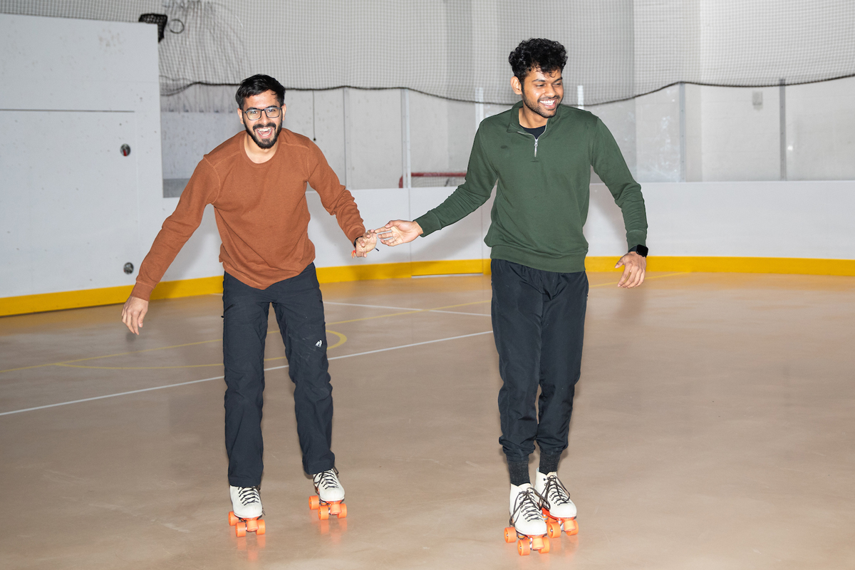 Two students share a laugh while rollerskating.