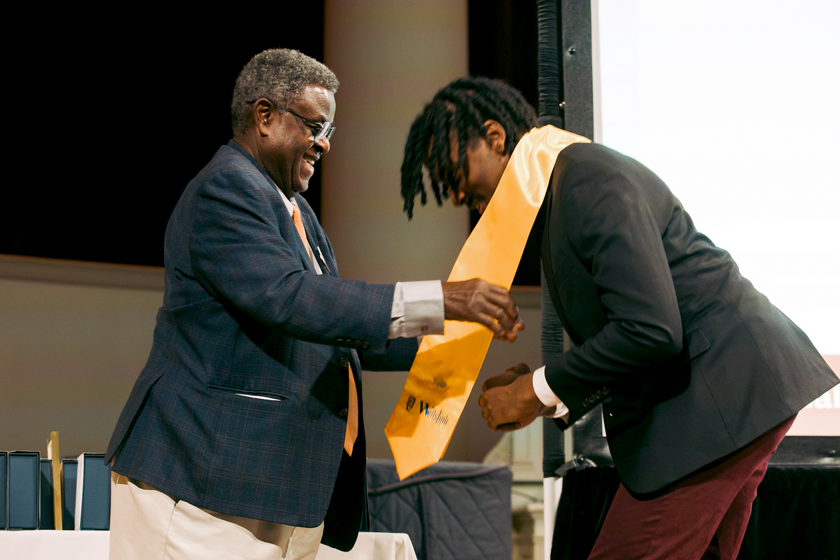 A student is presented with a commemorative Orange sash.