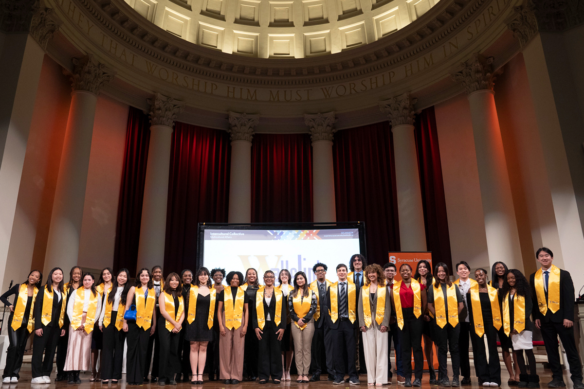 Students pose with their Orange commemorative sashes on stage at Hendricks Chapel.