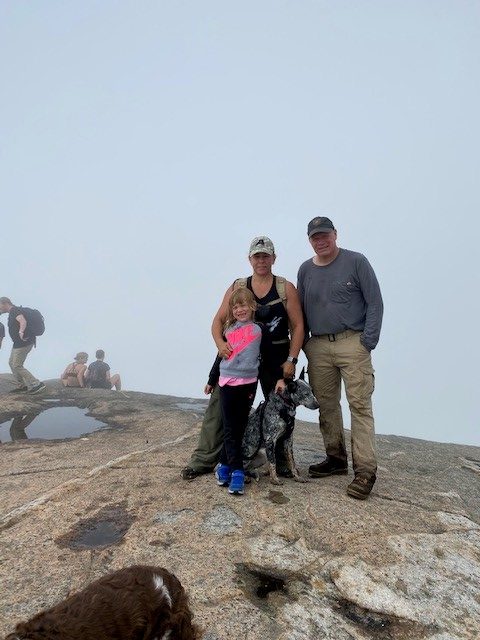 three people standing on a mountain