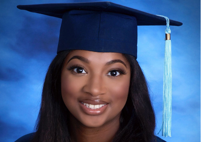 A woman poses for a photo wearing her cap and gown.