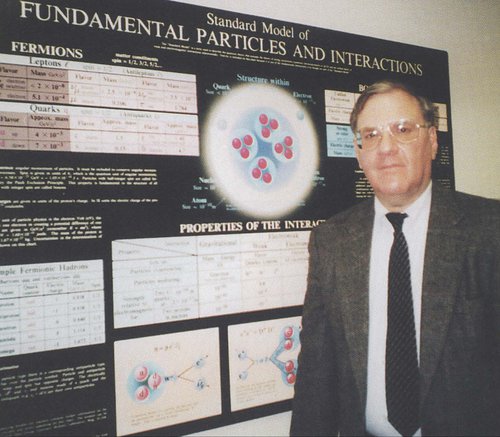 person standing in front of a research poster that says Fundamental Particles and Interactions