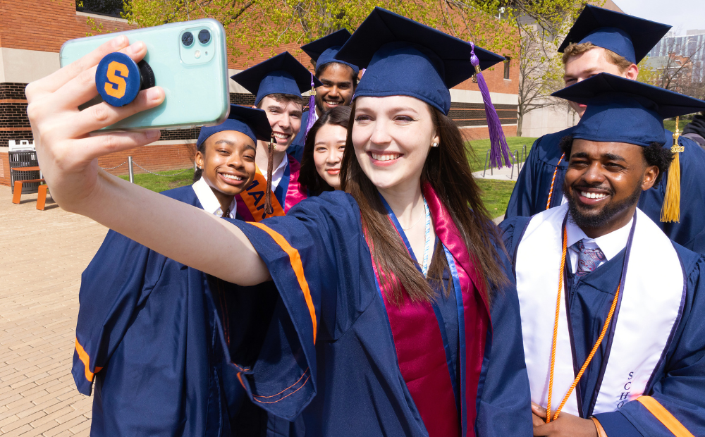 A group of Syracuse University students take a selfie by the Schine Student Center.