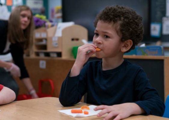 Elbridge Elementary School student eating orange.