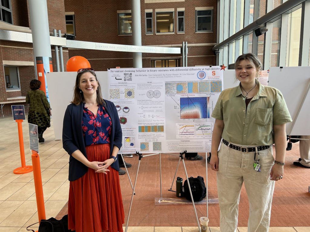 two people stand in front of a research poster