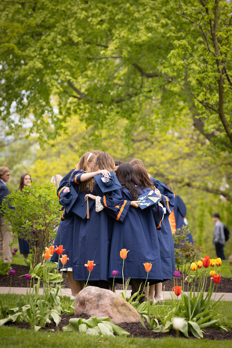 Graduates standing in a circle giving each other a hug