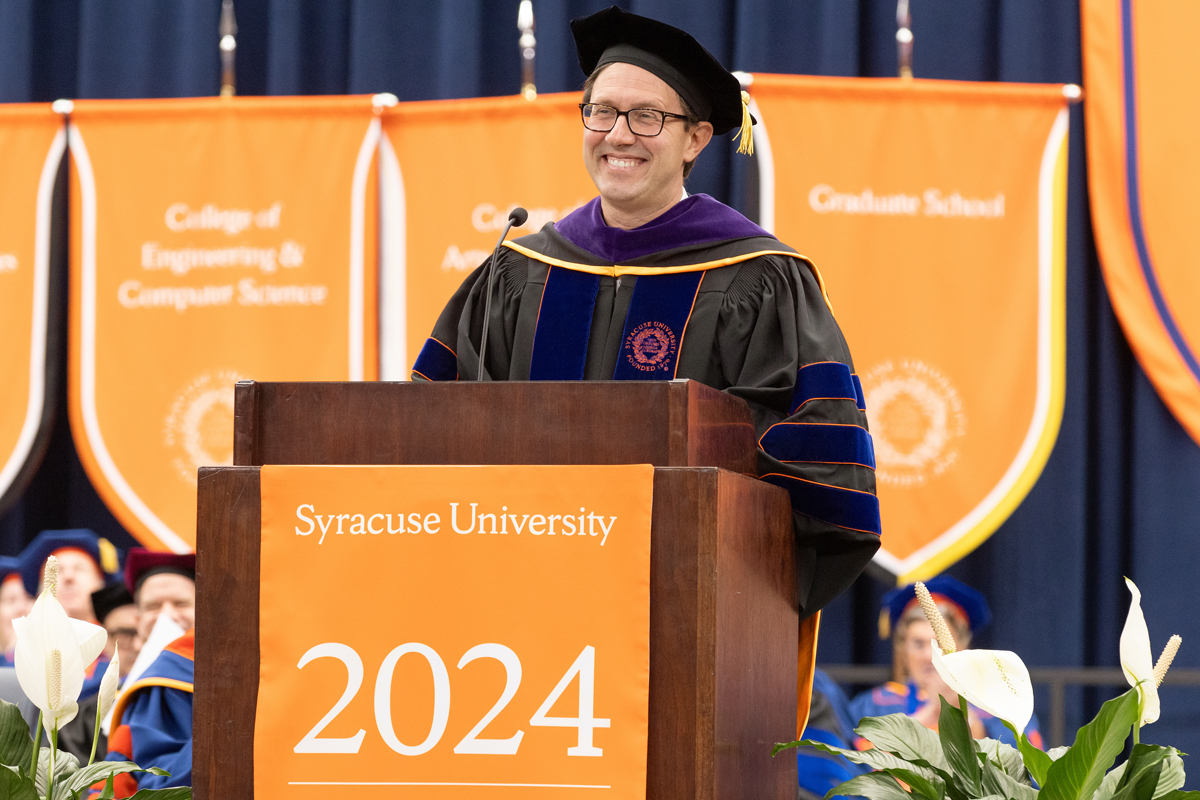 A man smiles while delivering the keynote address during Syracuse University's Commencement.