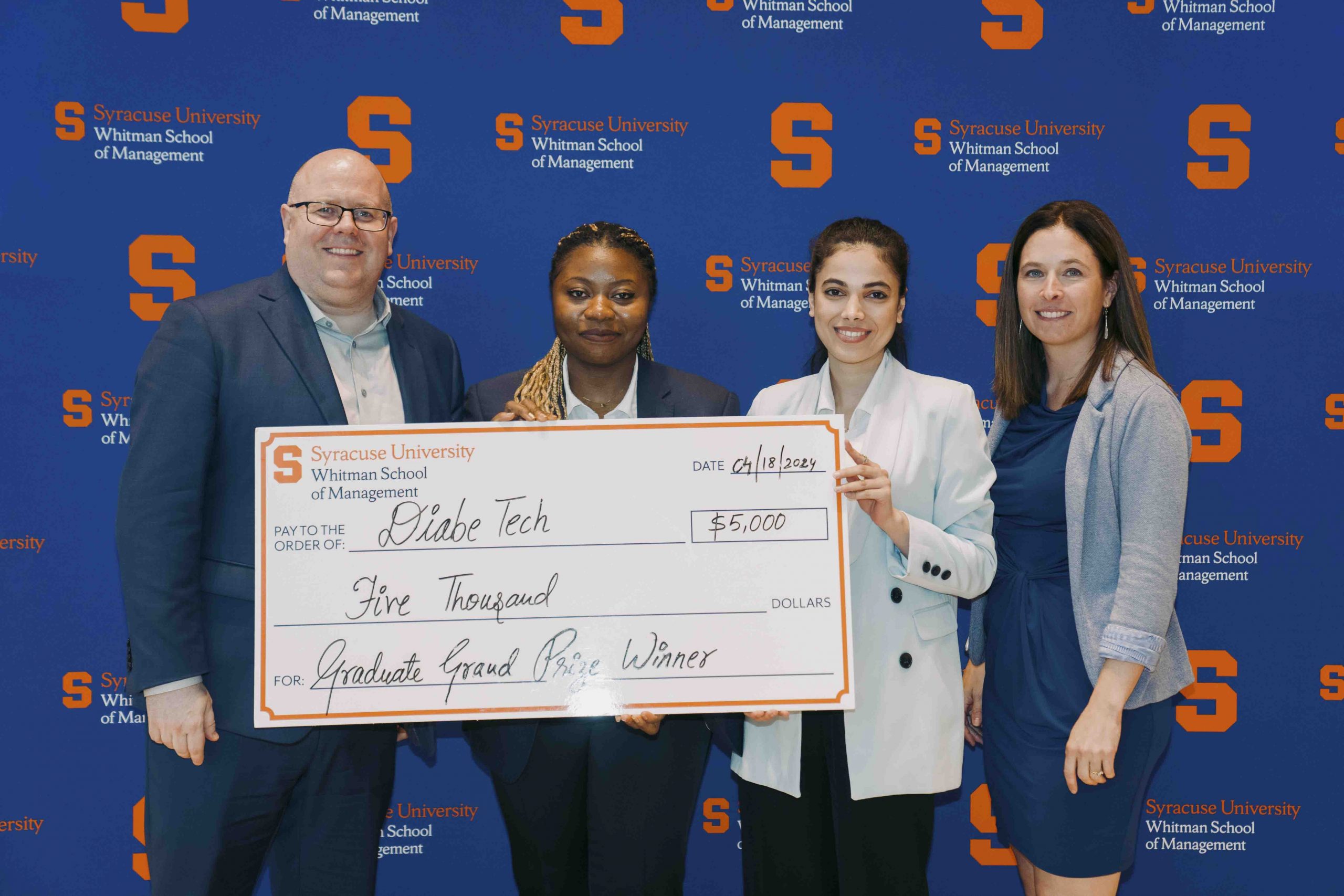 Four people standing together holding an oversized check