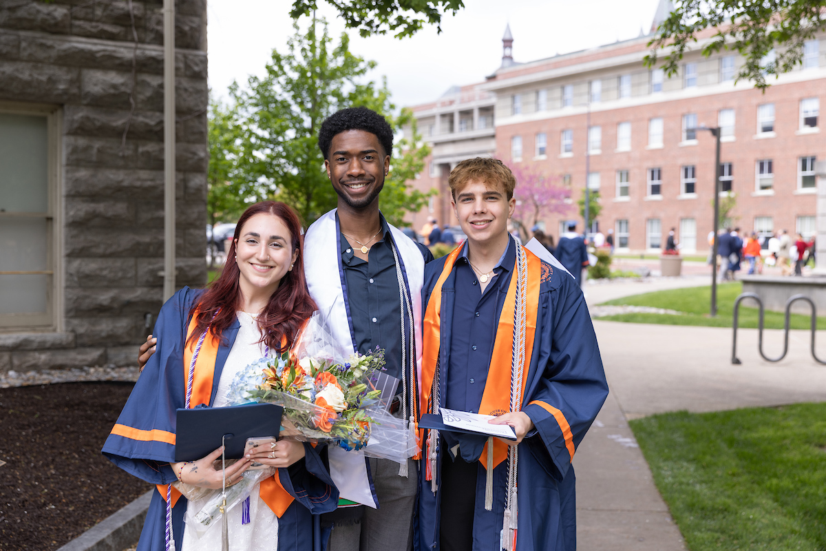 Three students standing together after Commencement outside on the Quad