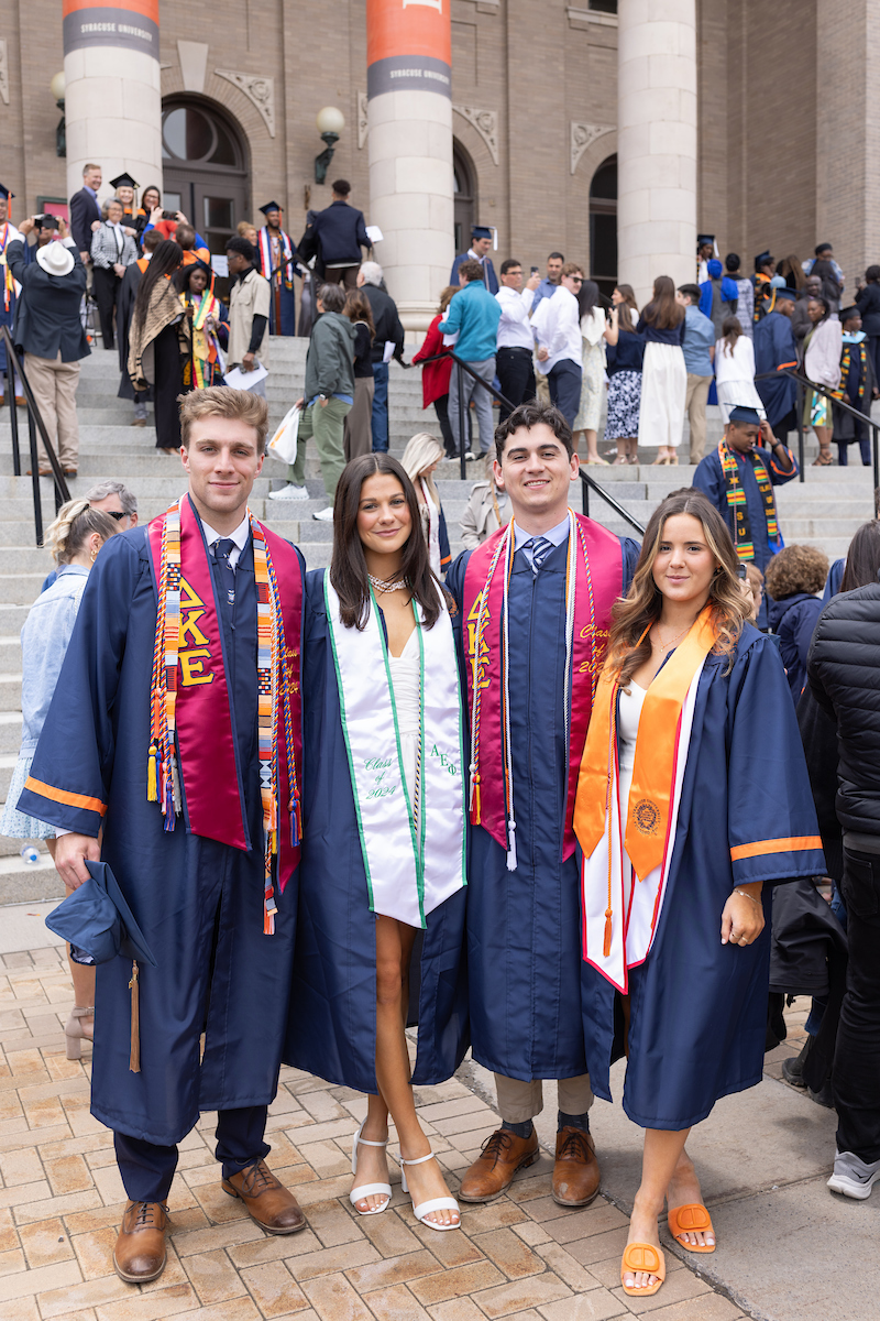 Four students standing together in caps and gowns