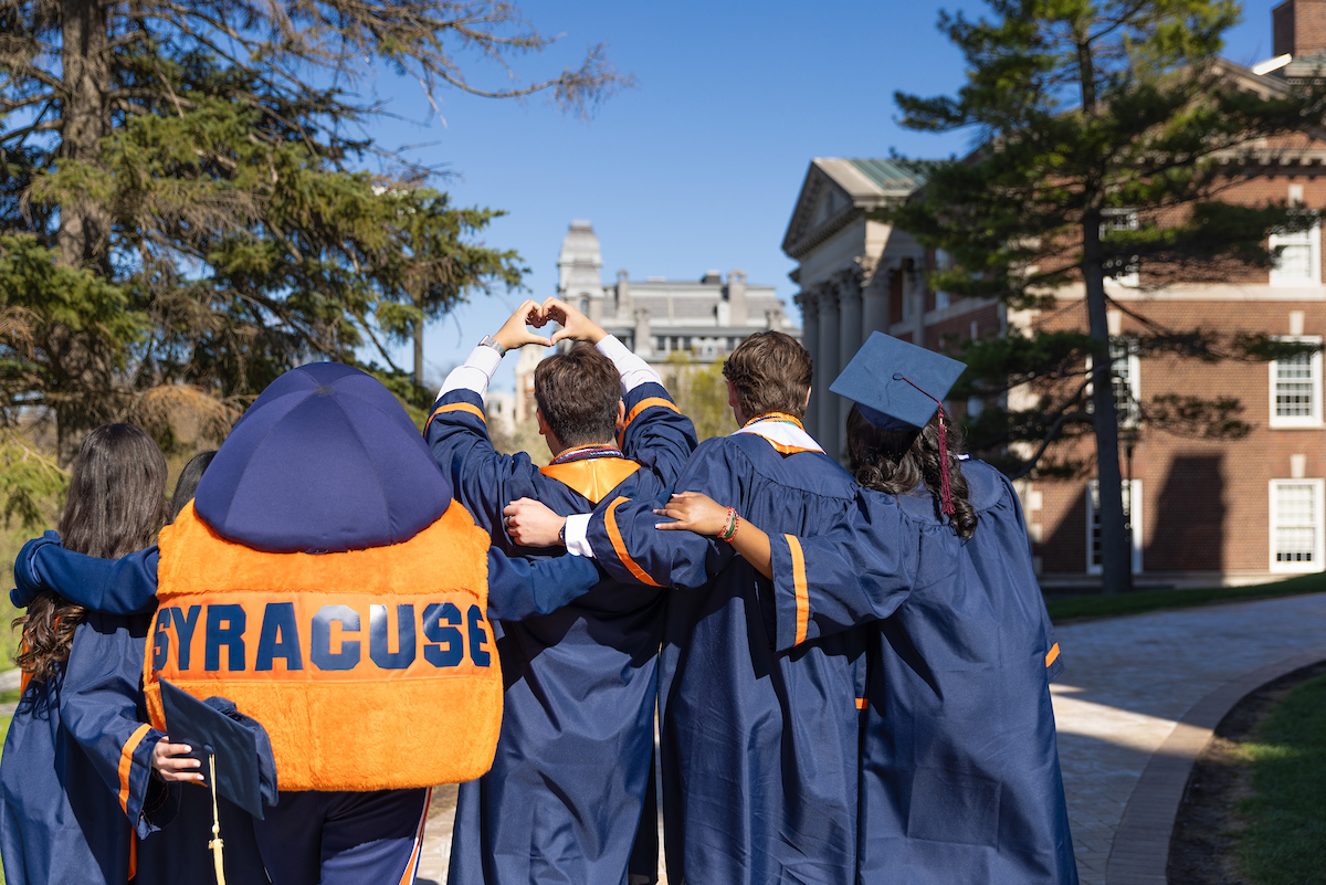 Students in navy blue caps and gowns with Otto