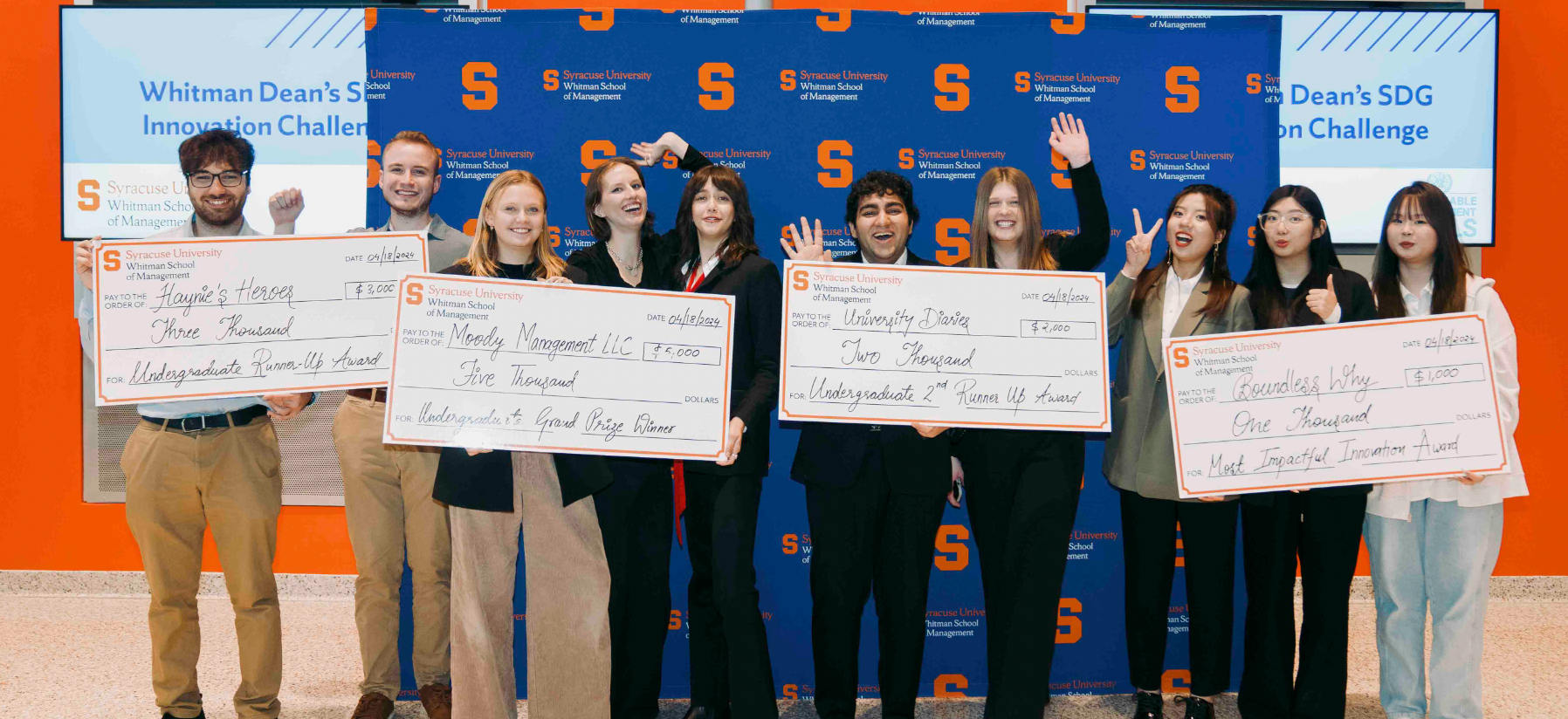 Four sets of groups of students holding oversized checks