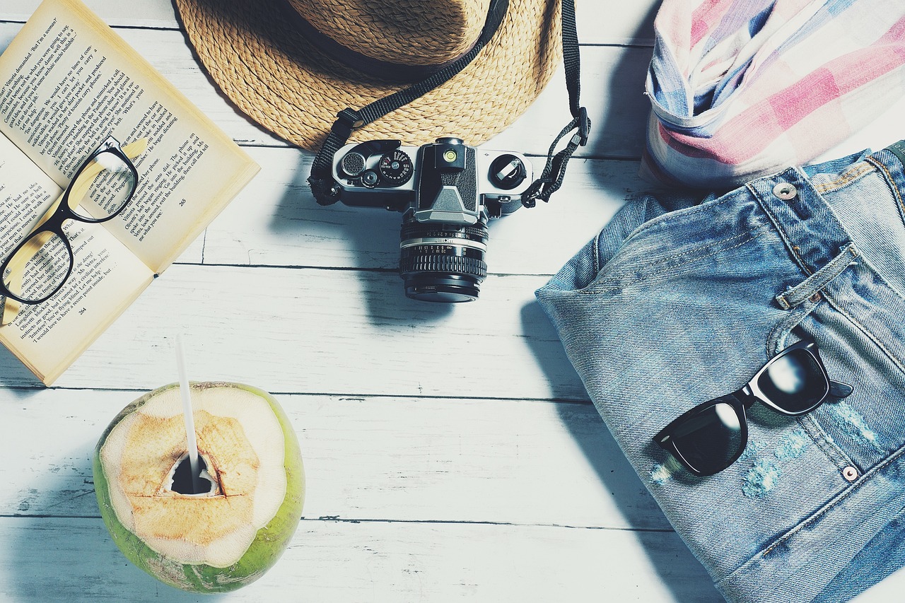 coconut, shorts, sunglasses, hat, book, camera, towel and reading glasses