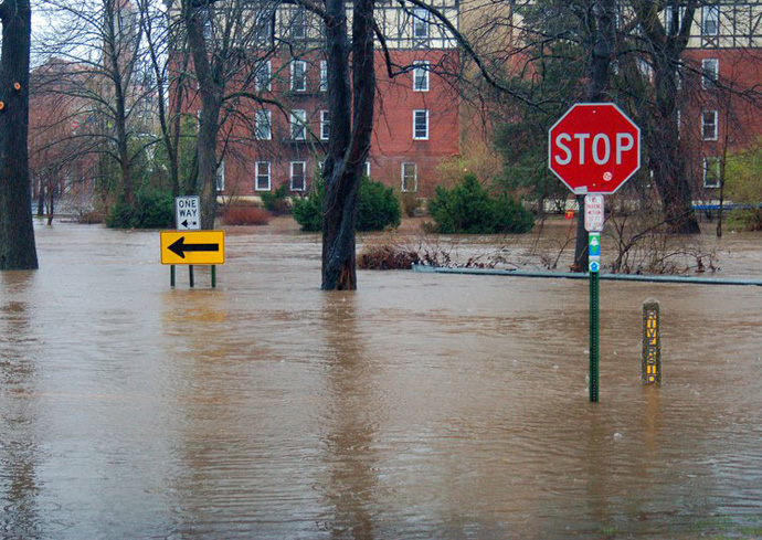 Flooded roadway with stop sign and building in the background