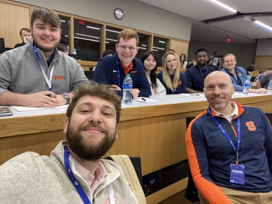 A professor poses with his electronic sports students in a classroom.