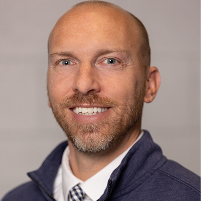 A man smiles while posing for a headshot.