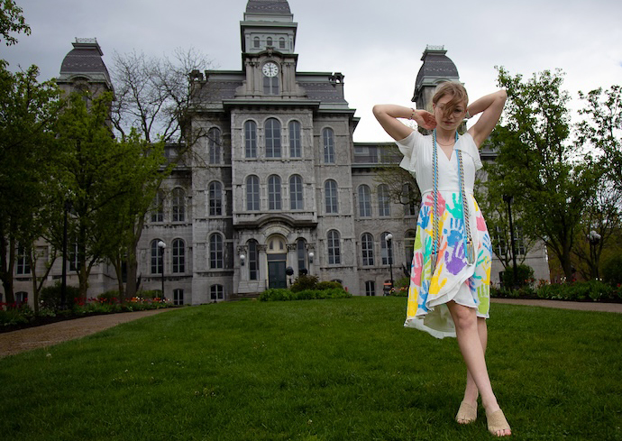 A woman poses for a photo in front of the Hall of Languages while wearing a hand-printed dress.