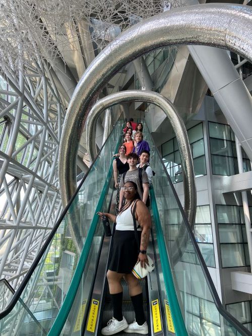 students on an escalator in a futuristic looking structure