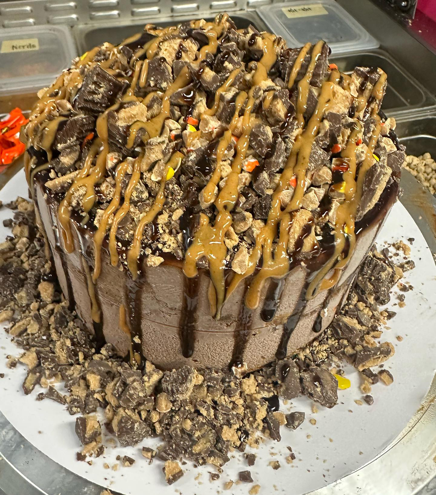 Chocolate ice cream cake covered with peanut butter and chocolate sauce and crushed up Reese pieces.