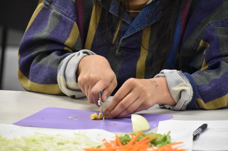 Person chopping ginger on a purple cutting board.