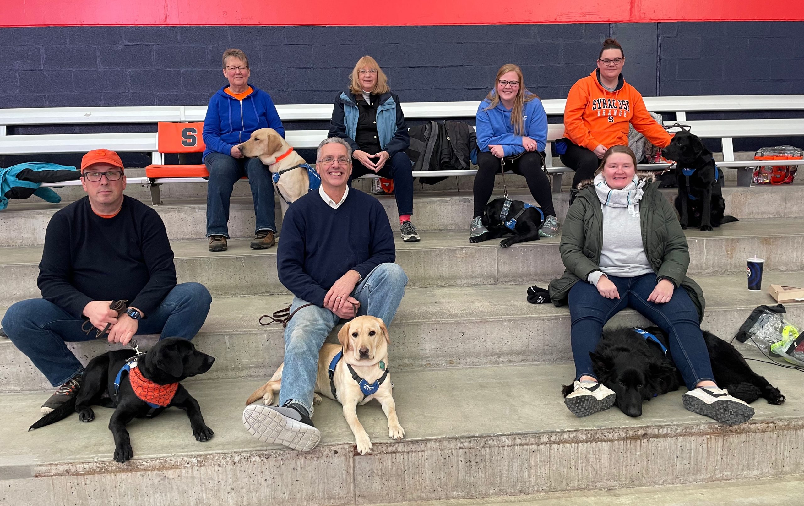 Group of people sitting on bleachers with puppies in the JMA Dome. 