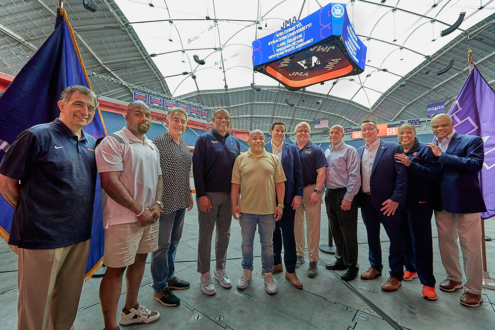 group of Syracuse University and local leaders gather together at the JMA Dome during a press conference