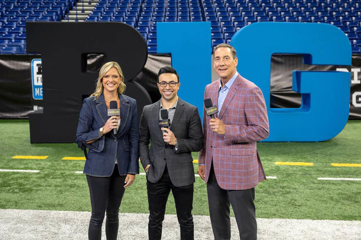 Three television broadcasters stand on a football field with the Big Ten logo in the background.