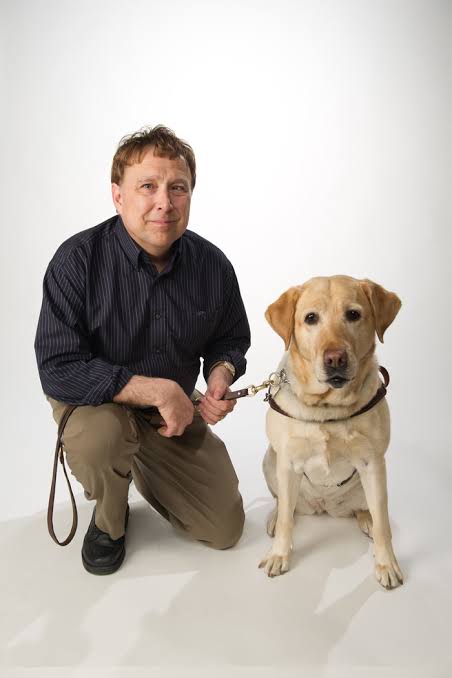 Man kneeling next to a dog.