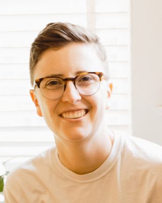 Headshot of a person in glasses smiling