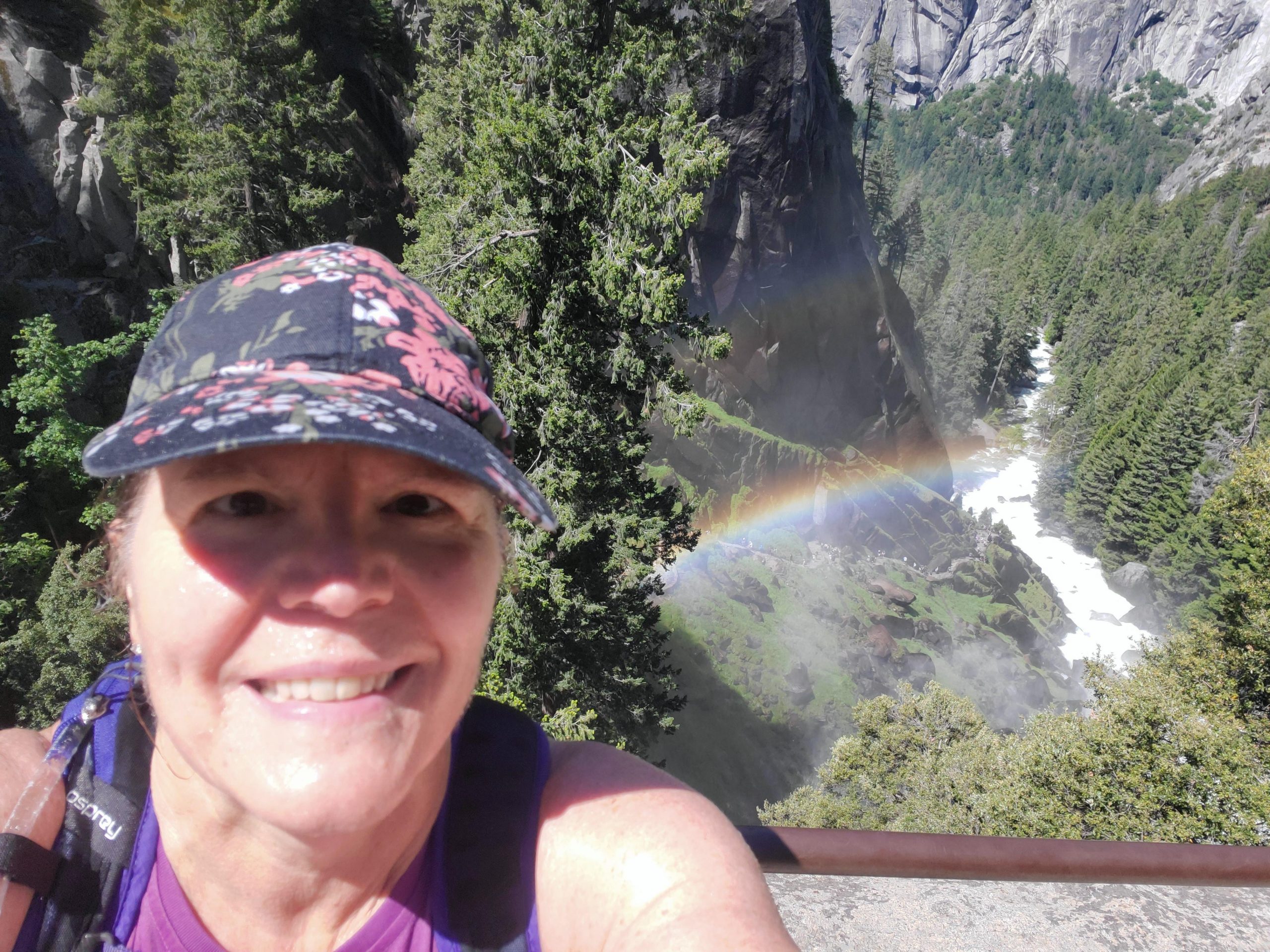 Person taking a selfie with a rainbow in the background.