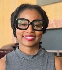 Woman with slicked back hair and large black glasses