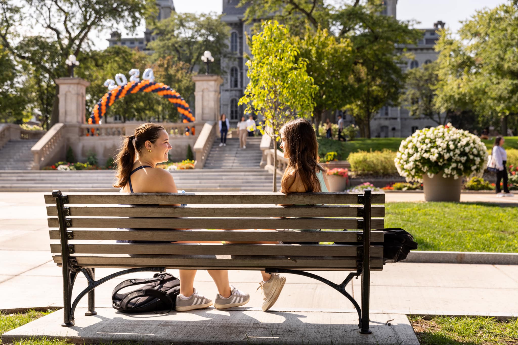 Two people sitting on a bench talking to each other on the promenade. 