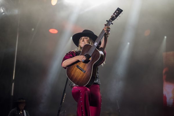 Woman performs on stage holding a guitar