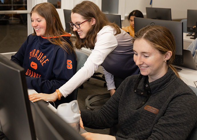 three students from the sports analytics women's club working on the computer