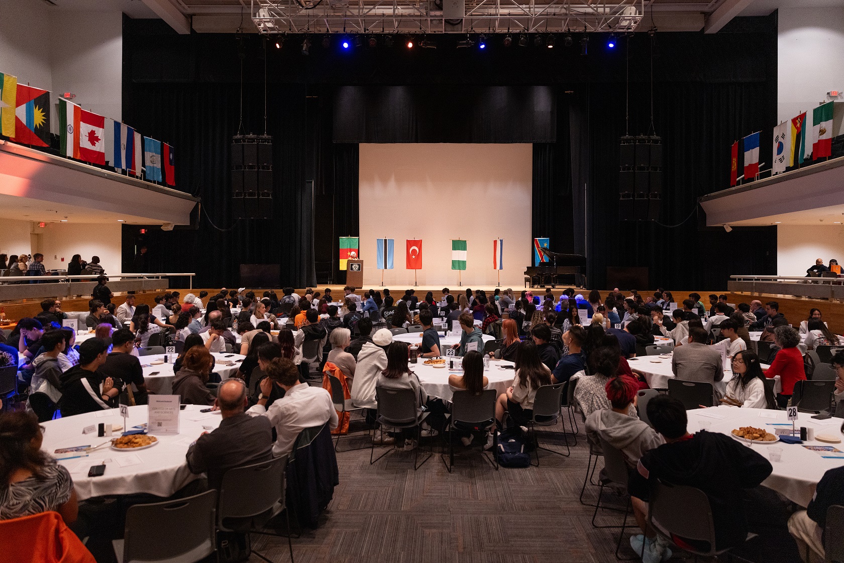 people seated at tables in large auditorium