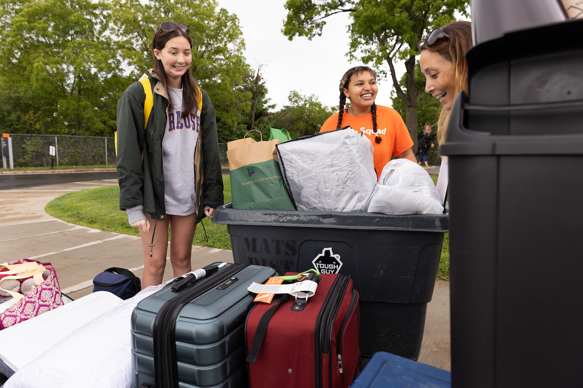 Three people unloading a car. 