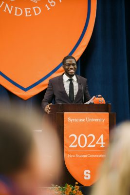 Person standing at a podium speaking.