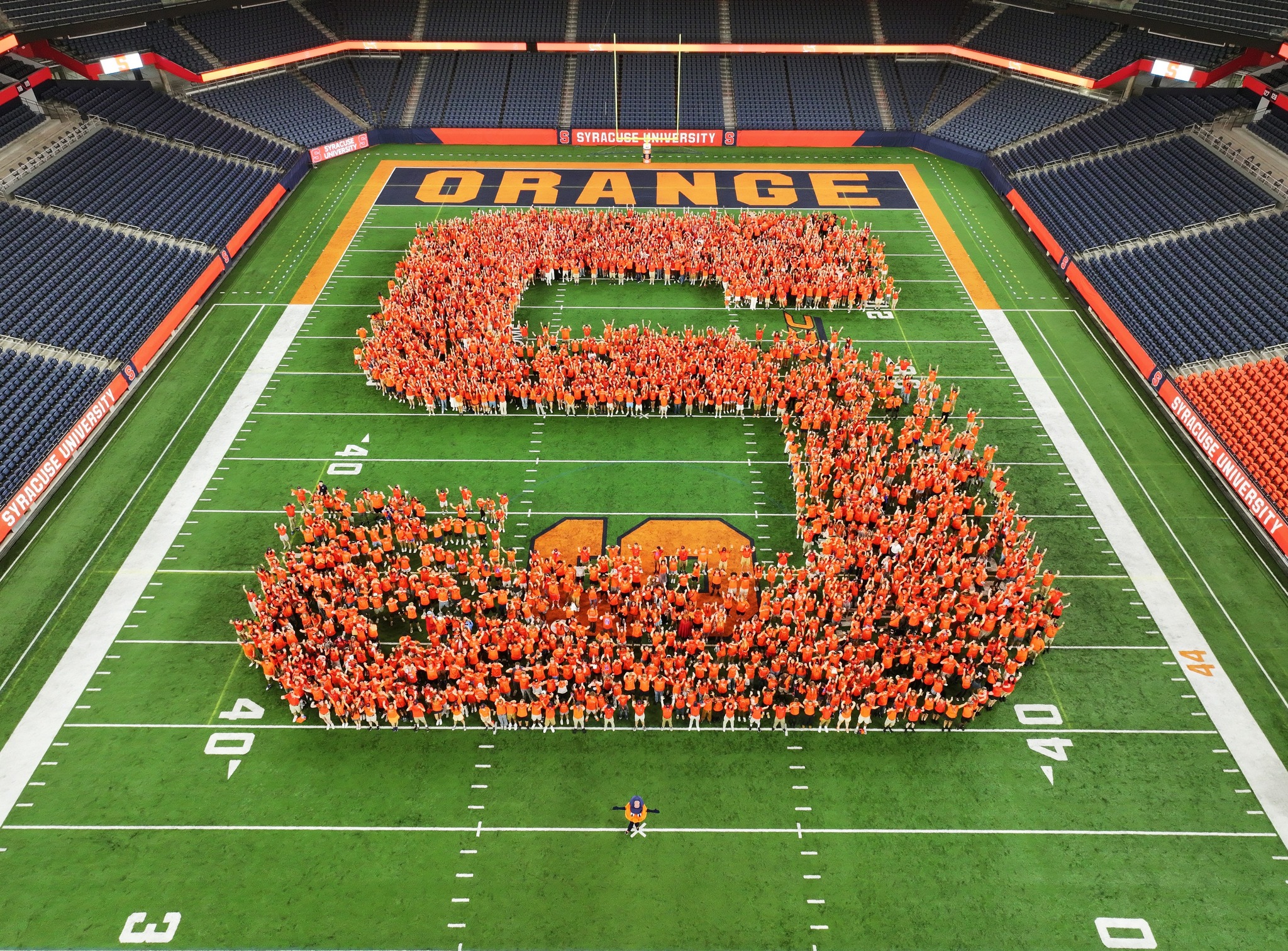 Students stand together and form the shape “S” on the field 