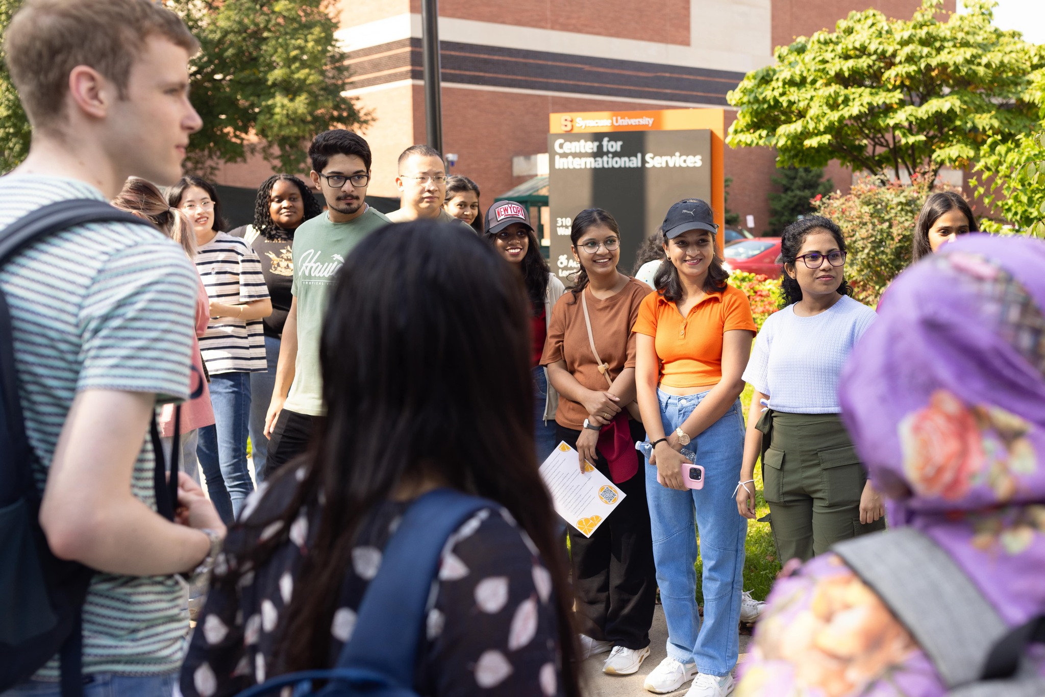 A group of people stand in a circle outside.