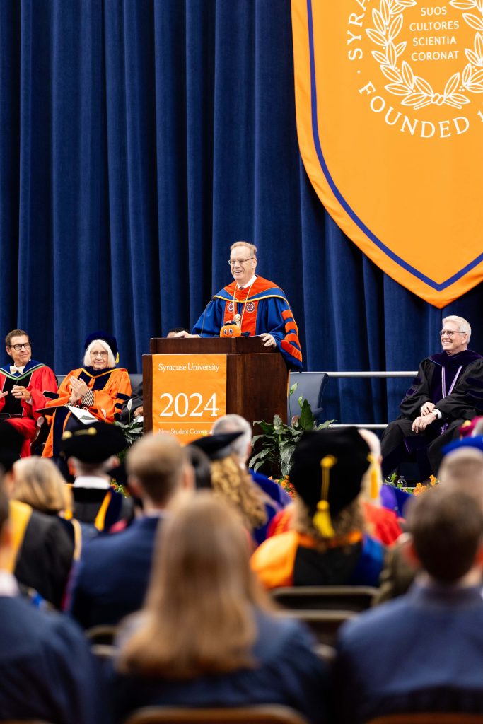 Chancellor standing at a podium on a stage speaking