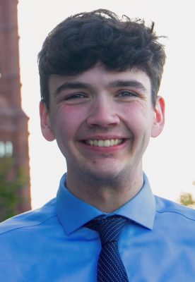 A man smiles for a headshot on campus.